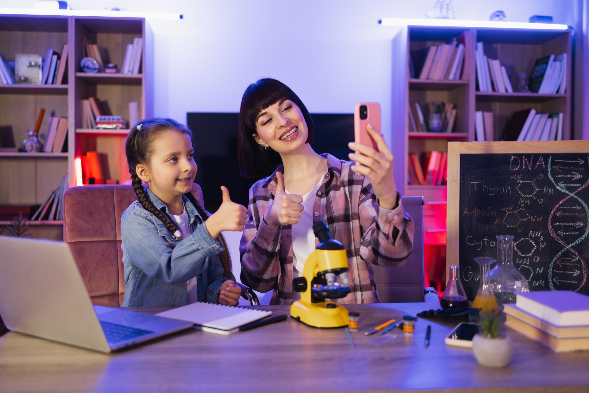 Two women engaged in biological research using modern microscope.